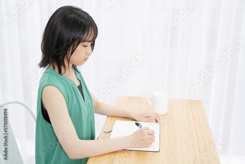 ノートに文字を書いている若い女性