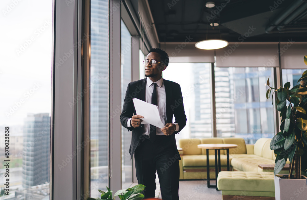 Fototapeta premium Serious black businessman with papers in office