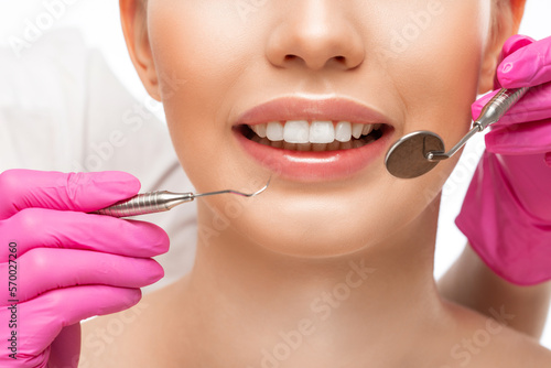 A dentist doctor treats caries on a tooth of a young beautiful woman in a dental clinic. Tooth filling.