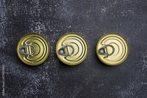 A trio of small circular ring-closed tins that are easy to open on a gray surface