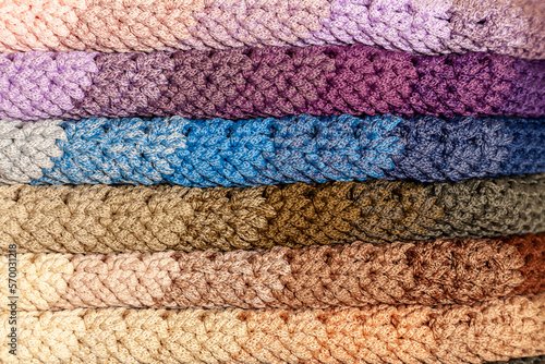Stacked multi-colored crocheted garment items.