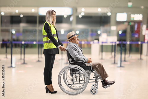 Female assitance worker at the airport standing with a passenger in a wheelchair photo