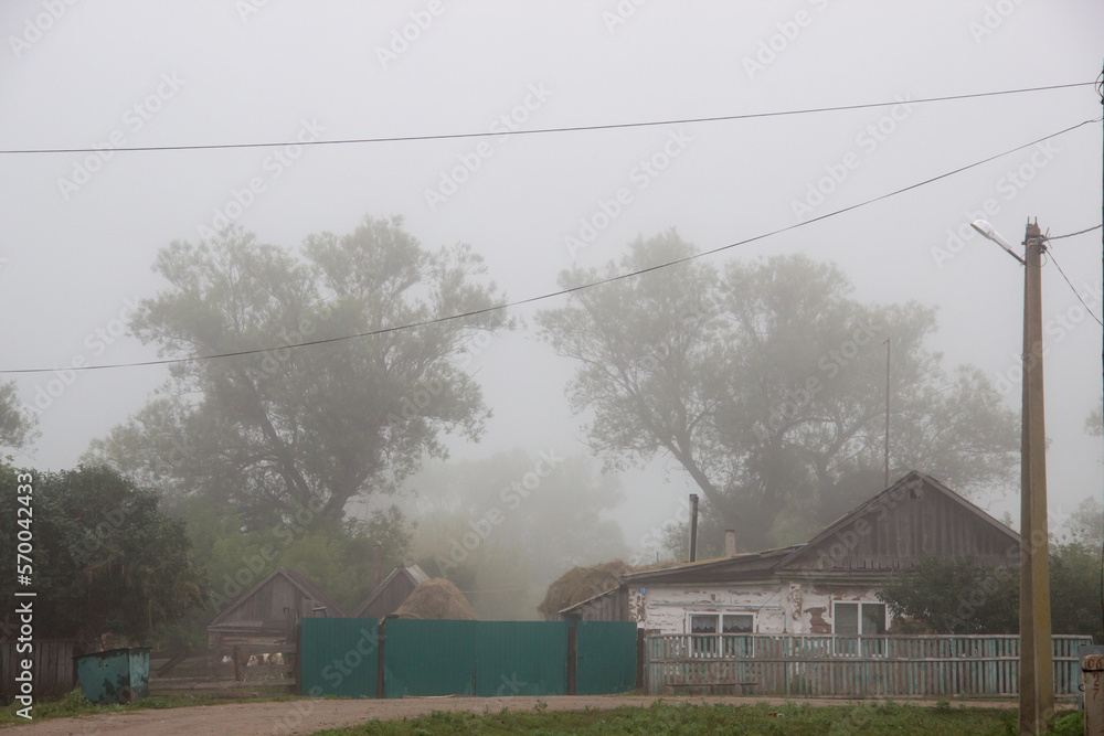 a foggy day in a rural area with houses and green trees