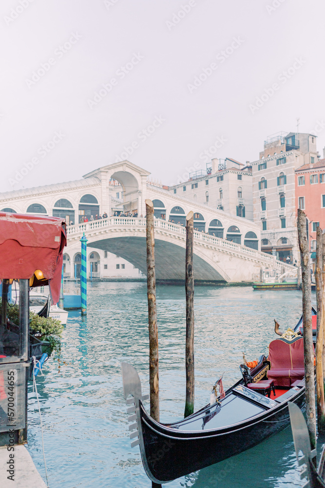 A gondola is docked in the blue water, waiting for its next passenger. In the background you can see the Rialto Bridge, whose stone shines white and invites you to stroll.