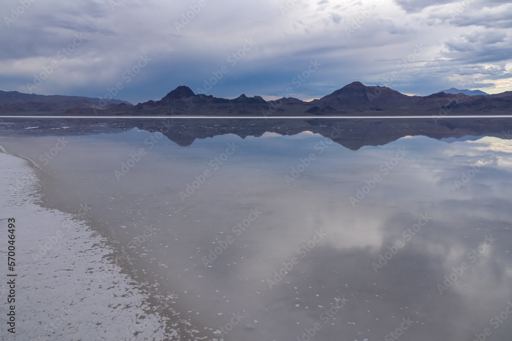Obraz premium Scenic view of beautiful mountains reflecting in lake of Bonneville Salt Flats at sunset, Wendover, Western Utah, USA, America. Looking at summits of Silver Island Mountain range. Romantic atmosphere