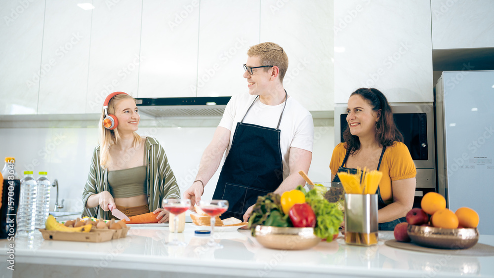 Cheerful family of young mother and father with their teenage daughter enjoying in modern kitchen while preparing healthy breakfast and juice while tasting food Cheerful family of young mother and father with their teenage daughter enjoying in modern kitchen while preparing healthy breakfast and juice while tasting food