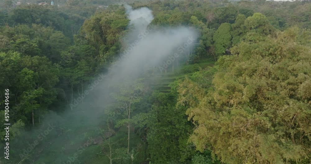 Aerial Forward Shot Of Smoke Spreading Over Tranquil Green Hill - Java, Indonesia Aerial Forward Shot Of Smoke Spreading Over Tranquil Green Hill - Java, Indonesia