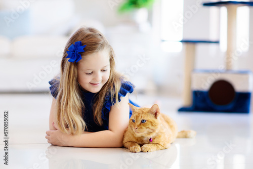 Child playing with cat at home. Kids and pets.