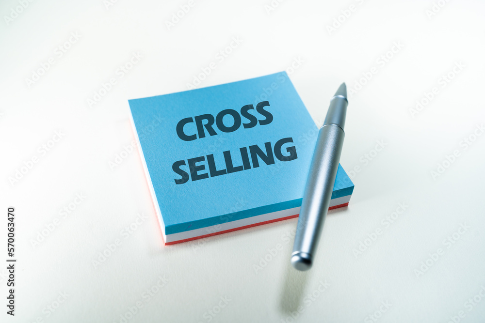 Fototapeta premium Cross selling word write in a post it with a silver pen. Business concept. Selling concept. Commerce concept.