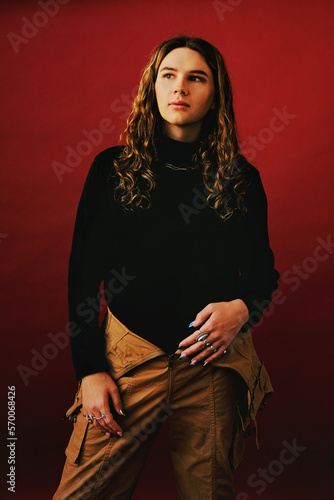 Non-Binary adult with long wavy hair against red background photo