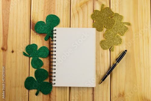 Image of green clover and white paper with copy space on wooden background