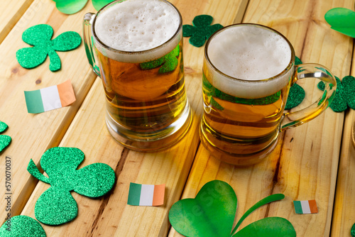 Image of beer glasses, clover and flag of ireland on wooden background