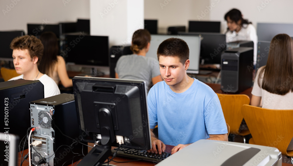 Fototapeta premium Modern boy student learning basics of programming in group course in computer college