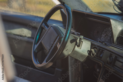 Old and worn steering wheel of an older car. Rectangular shape of steering wheel centre, plastic car interior.