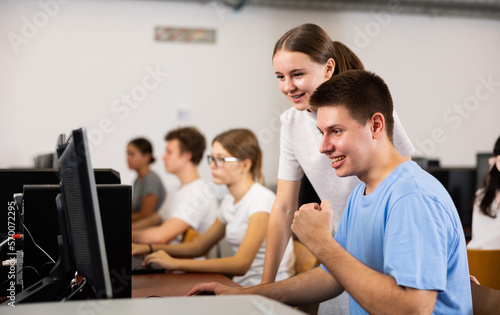 Positive young student emotionally reacting while working at pc in computer class of university