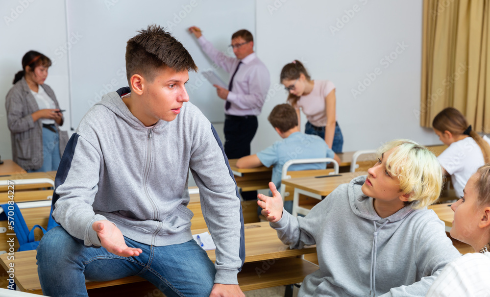 Obraz premium Group of smiling teen pupils chatting in break between lessons indoors