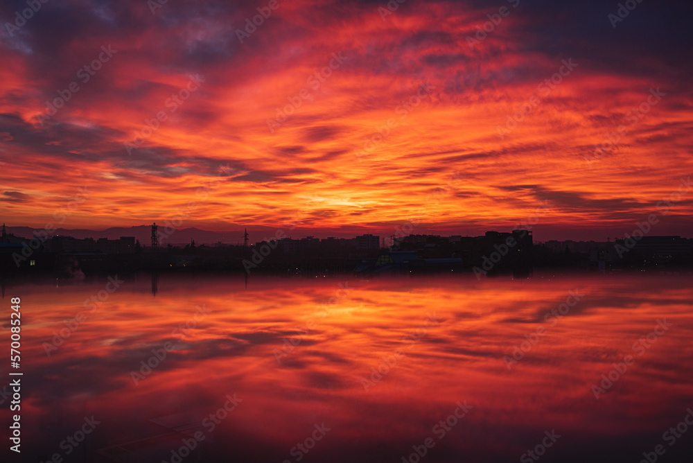 dramatic sunset reflection, orange and cloudy sky