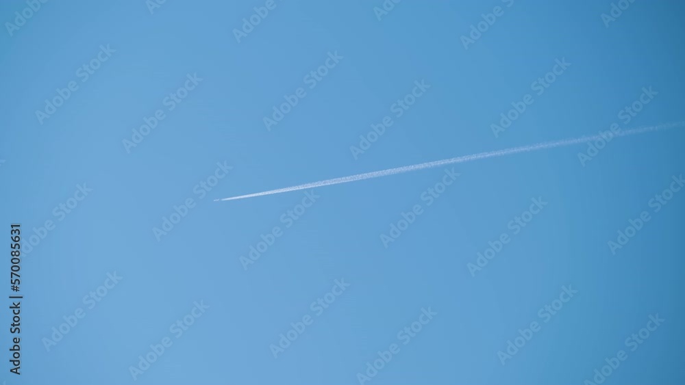 Distant passenger jet plane flying on high altitude on clear blue sky leaving white smoke trace of contrail behind. Air transportation concept Distant passenger jet plane flying on high altitude on clear blue sky leaving white smoke trace of contrail behind. Air transportation concept