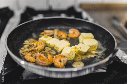 Shrimps fried in butter in frying pan for spicy chilli sauce dish. Restaurant kitchen food preparation process. Horizontal indoor shot. High quality photo