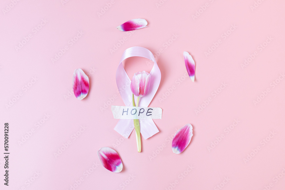 Pink ribbon with tulip and petals on a pink background. Pink ribbon with tulip and petals on a pink background.