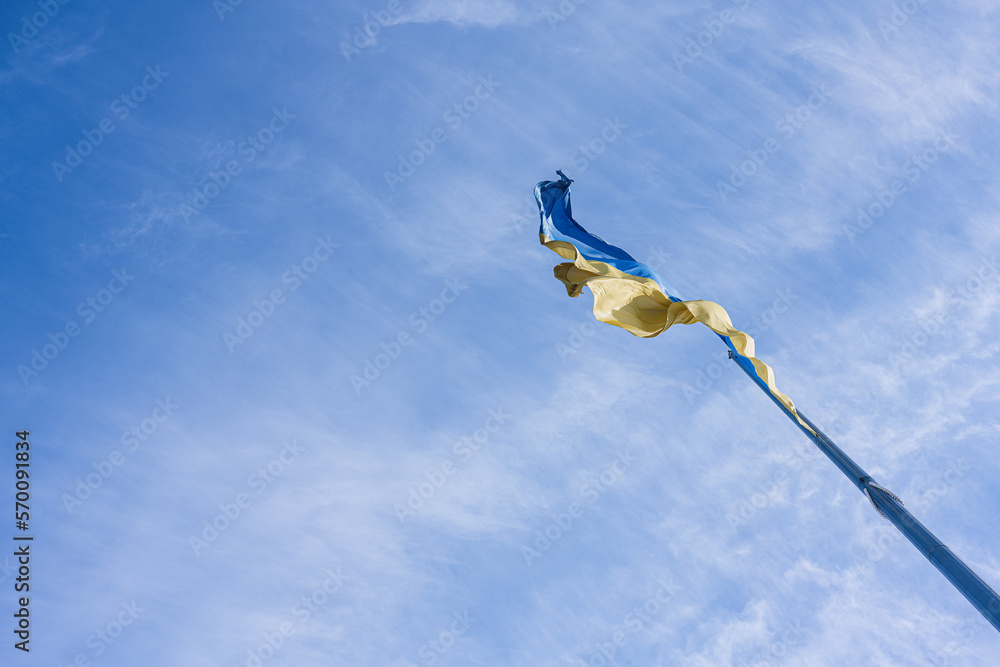 Flagpole with the Ukrainian flag against blue sky.