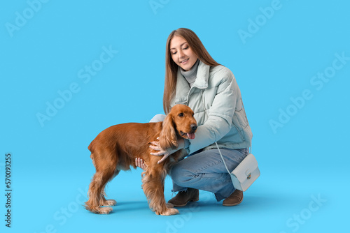 Young woman with red cocker spaniel on blue background