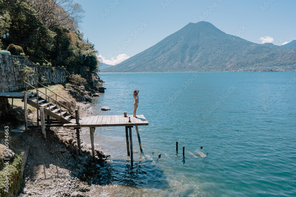 Young woman standing on the dock at Lake Atitlan - Traveler enjoying summer on the lake - Lake Atitlan Guatemala