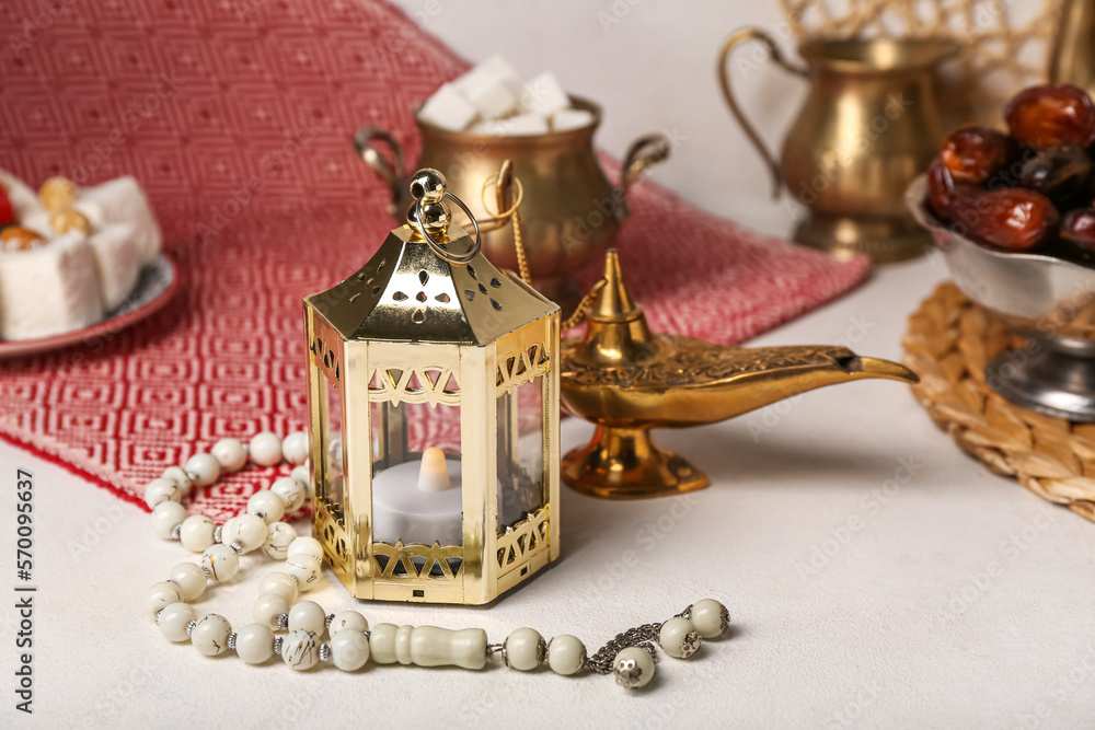 Muslim lantern with candle and prayer beads for Ramadan on light table, closeup Muslim lantern with candle and prayer beads for Ramadan on light table, closeup