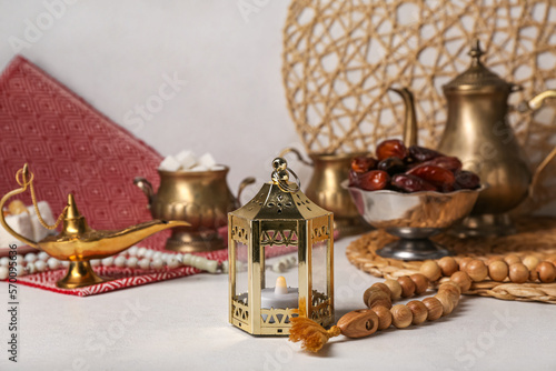 Muslim lantern with candle and prayer beads for Ramadan on light table, closeup photo