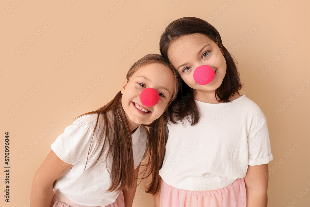 Little girls with clown noses on beige background. April Fools' Day celebration Little girls with clown noses on beige background. April Fools' Day celebration
