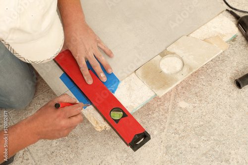 Worker installing tiles indoors, closeup. Home improvement