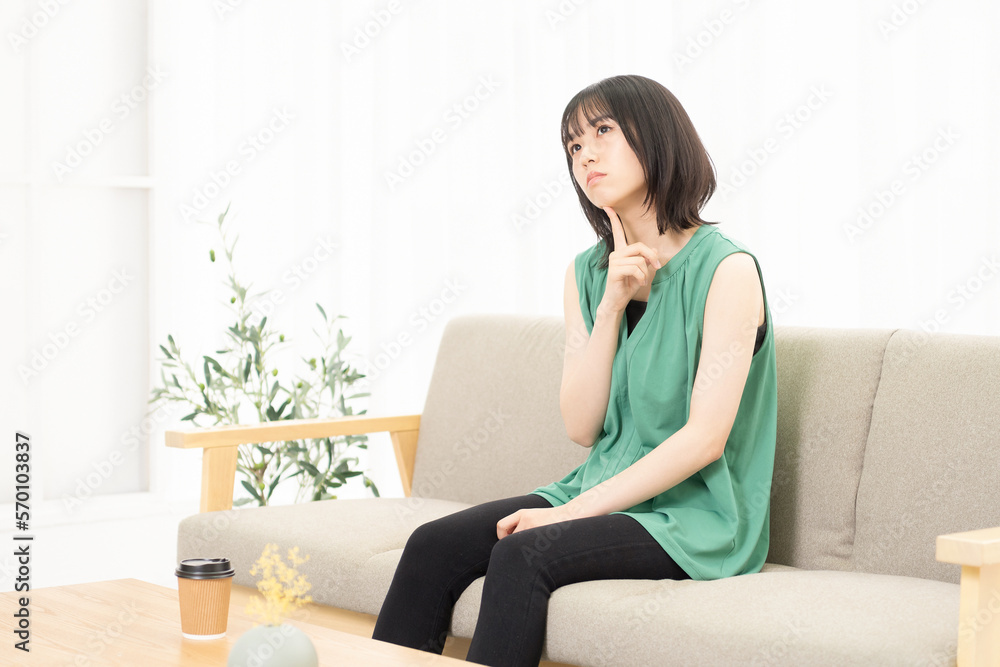 ソファに座って考え事をしている若い女性 ソファに座って考え事をしている若い女性