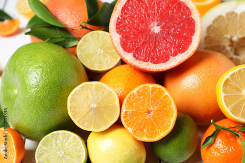 Different citrus fruits with fresh leaves, closeup