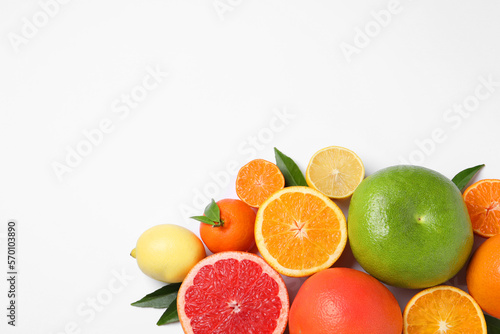 Different citrus fruits with fresh leaves on white background, top view. Space for text