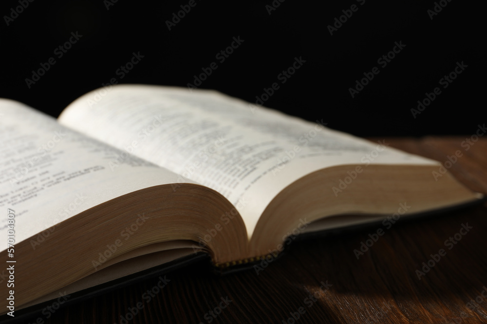 Open Bible on wooden table against black background, closeup Open Bible on wooden table against black background, closeup