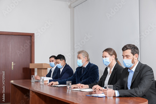 Business conference. People with protective masks working at table in meeting room