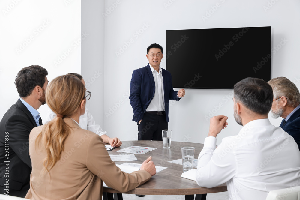 Business conference. Group of people listening to speaker report near tv screen in meeting room - obrazy, fototapety, plakaty 