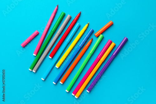 Many bright markers on light blue background, flat lay