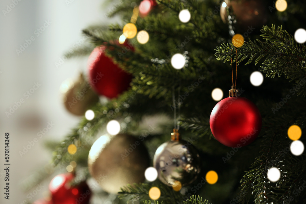 Christmas tree with beautiful baubles on blurred background, closeup. Space for text