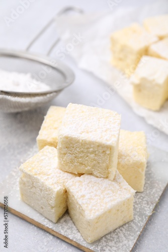 Delicious sweet marshmallows with powdered sugar on light grey table