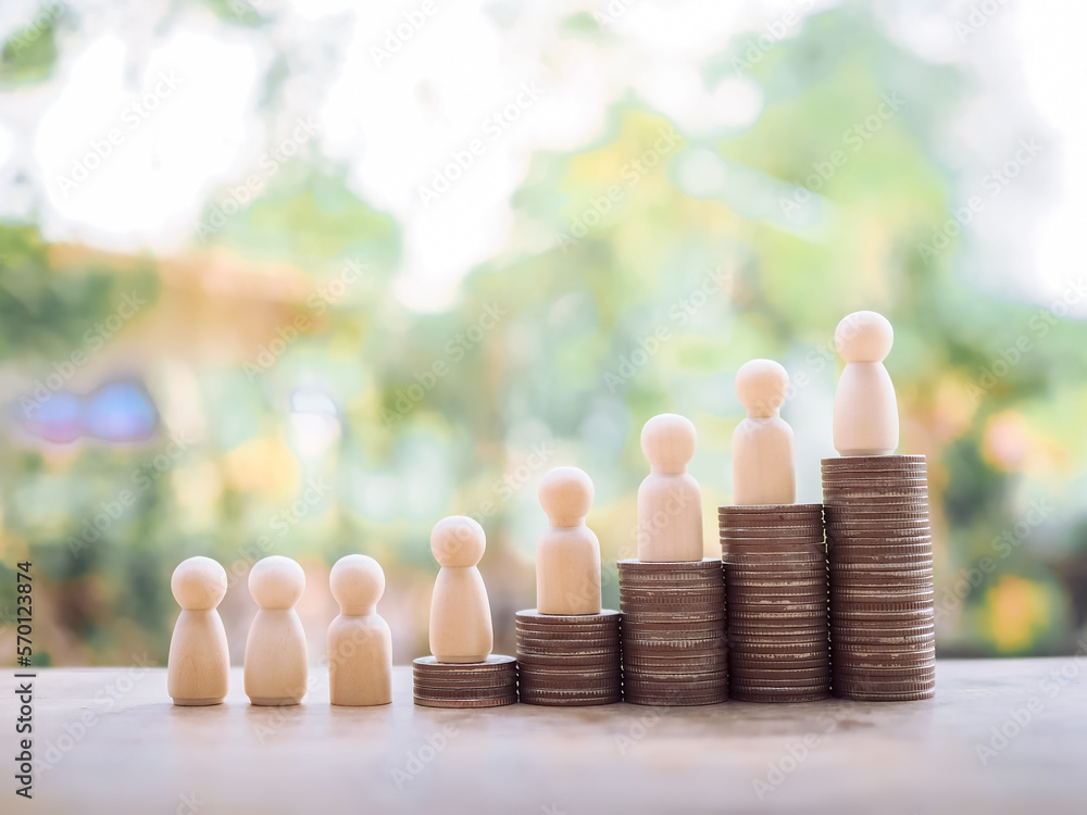 Wooden human figure on stack of coins for business concept Wooden human figure on stack of coins for business concept