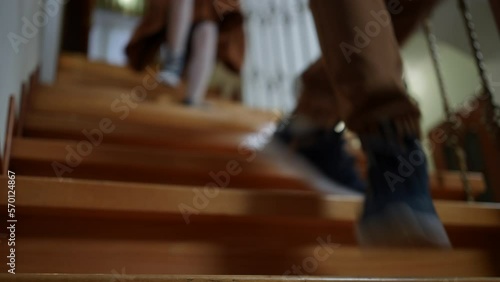 Unrecognizable boy and girl running downstairs in slow motion leaving. Caucasian brother and sister rushing for school in the morning