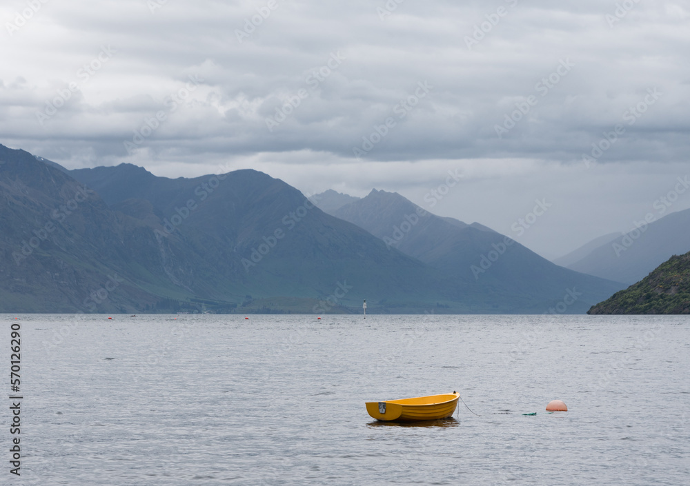 Isolated yellow row boat on Lake Wakatipu, amongst the mountains outside of Queenstown New Zealand