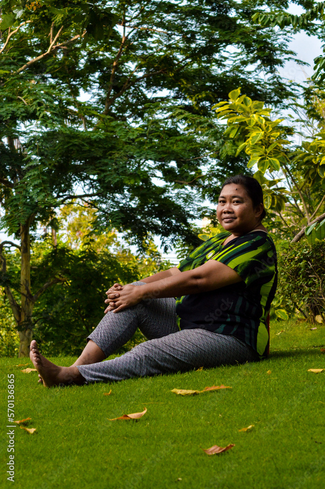 Portrait View A Woman Sitting Relaxed On The Grass Enjoying The Garden Atmosphere In The Afternoon Portrait View A Woman Sitting Relaxed On The Grass Enjoying The Garden Atmosphere In The Afternoon