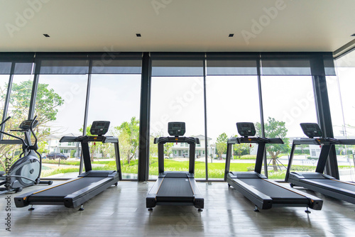 Treadmills set in gym interior. Fitness club with equipment. Sports background with glass windows