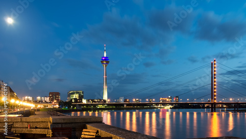 Skyline of Dusseldorf, the capital of the German federal state of North Rhine-Westphalia, in a beautiful sunset with the Rhine on the left and the Pegeluhr and St. Lambertus Basilika on the right.  © Mltz
