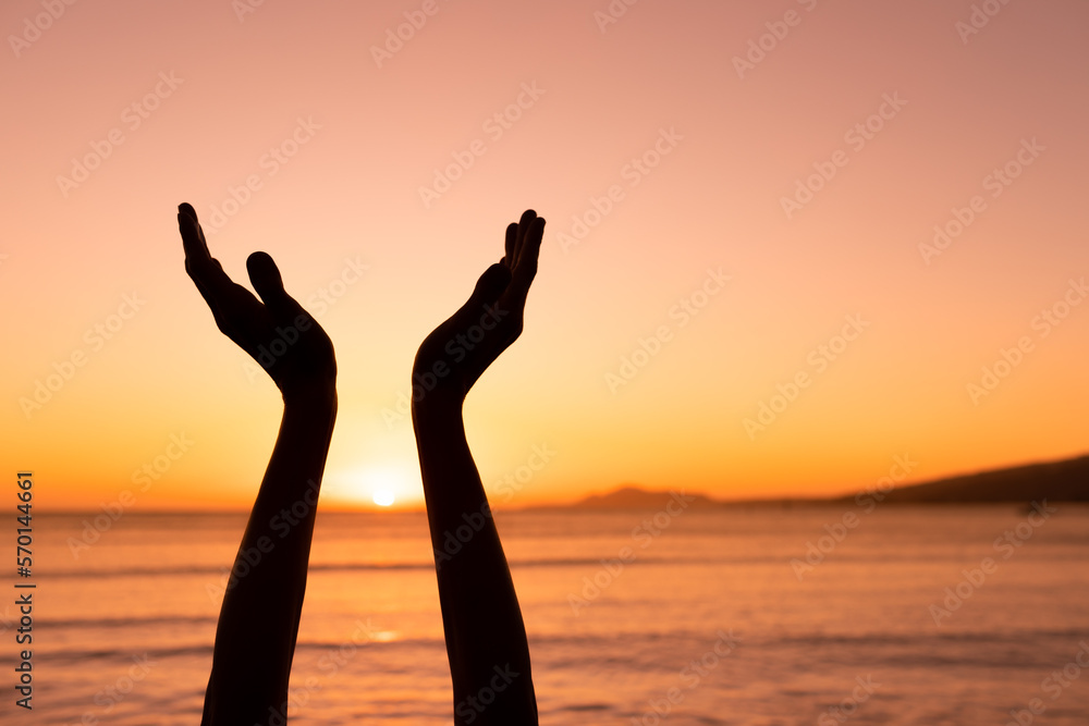 silhouette of a person with hands up to sunset at dawn 