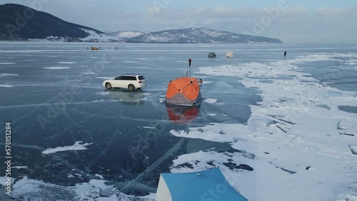 Flying a drone around an orange tent on the clear ice of Lake Baikal. Winter fishing on the largest lake