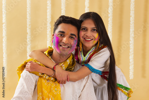 a young woman and man posing together with gulal on their faces while celebrating holi photo
