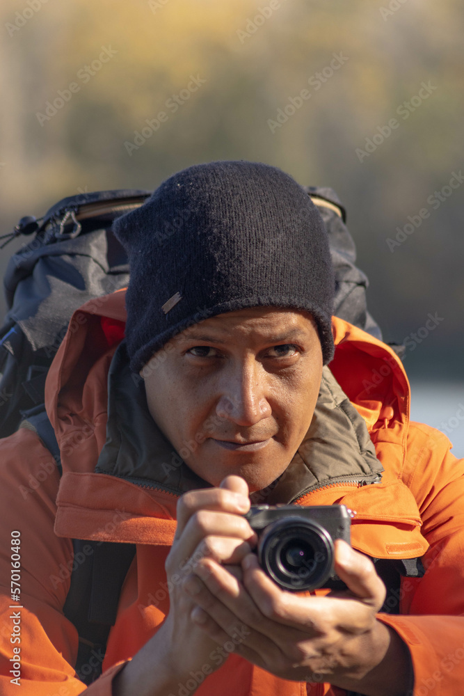 Obraz premium Portrait of traveler man at lake in autumn taking a photo with the digital camera